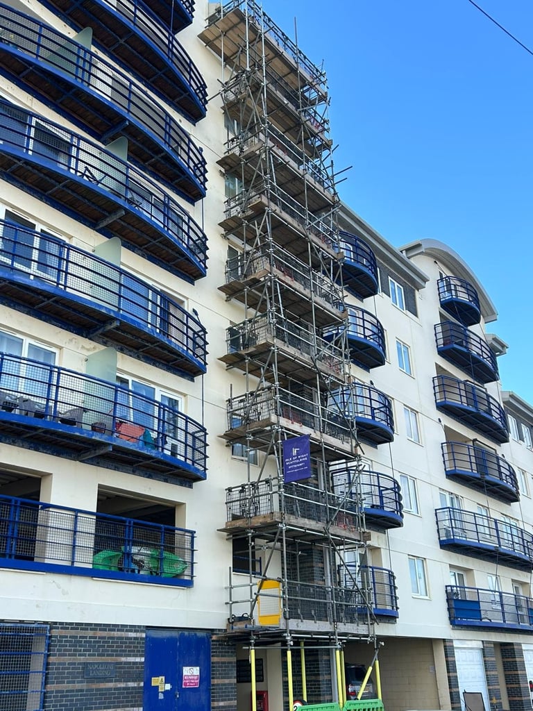 Modern apartment building facade with blue balconies and metal scaffolding for construction or renovation work